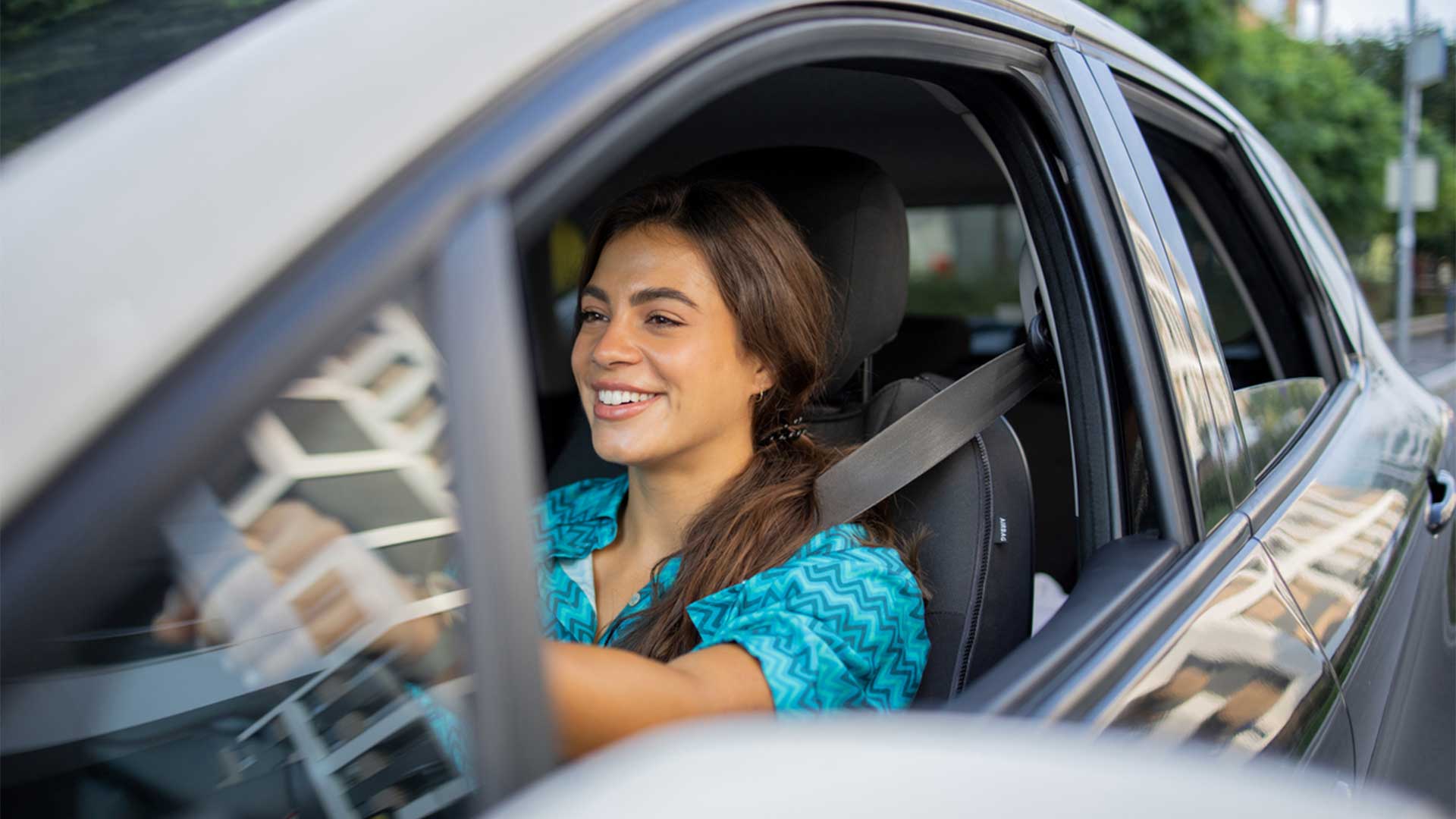 giovane donna sorridente alla guida di un'automobile