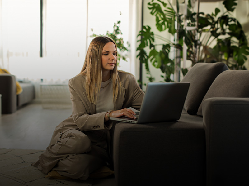 Fotografia di una giovane donna con un laptop nel salotto di casa