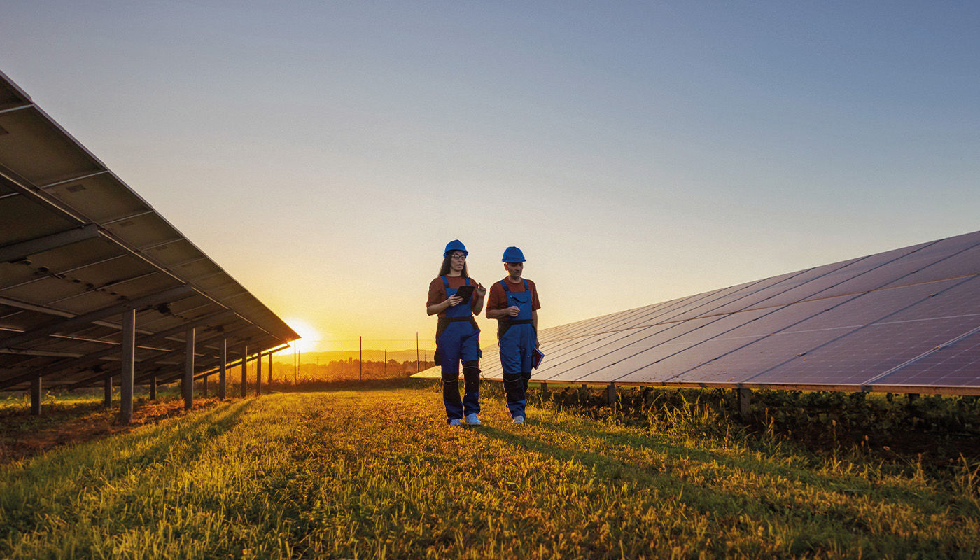 Operai che camminano su campo di pannelli fotovoltaici